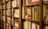 A cozy home library with rain and a passing storm.