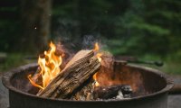 In the woods at dusk sitting next to a fire pit